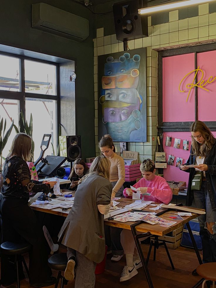 a group of people standing around a table with papers on it and pictures on the wall behind them