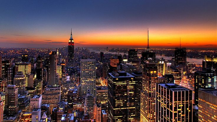 the city skyline is lit up at night with bright lights and skyscrapers in the foreground