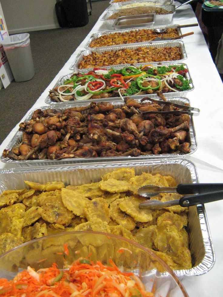 several trays of food are lined up on a long table with utensils