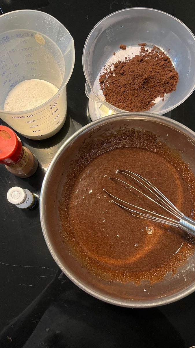 chocolate cake batter in a bowl with whisk and other ingredients on the table