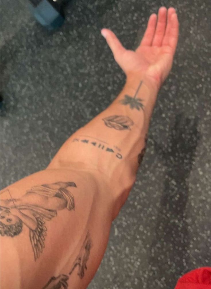 a person's arm with tattoos on it and one hand raised up to the sky