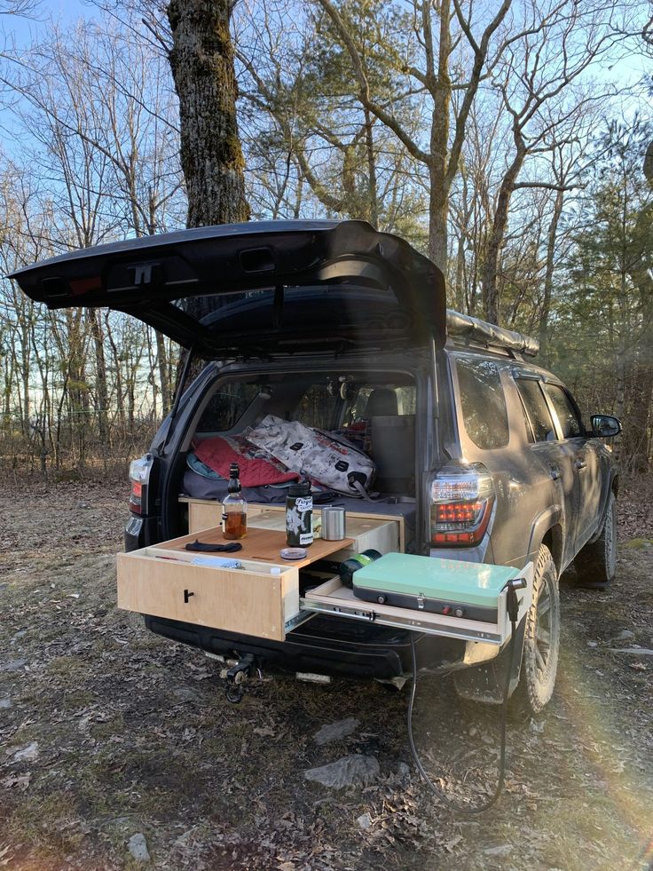 an suv parked in the woods with its trunk open