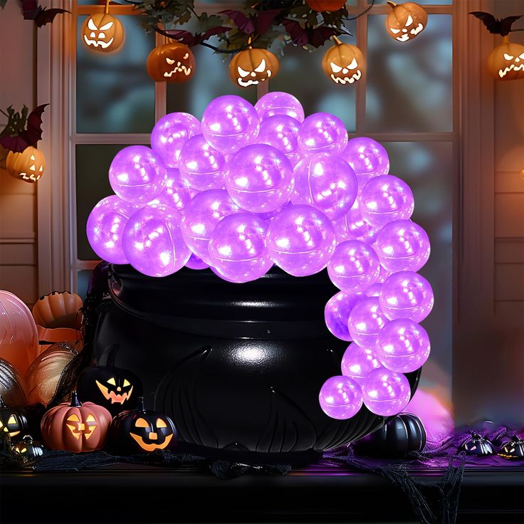 a large pot filled with purple balloons next to pumpkins and other halloween decorations in front of a window