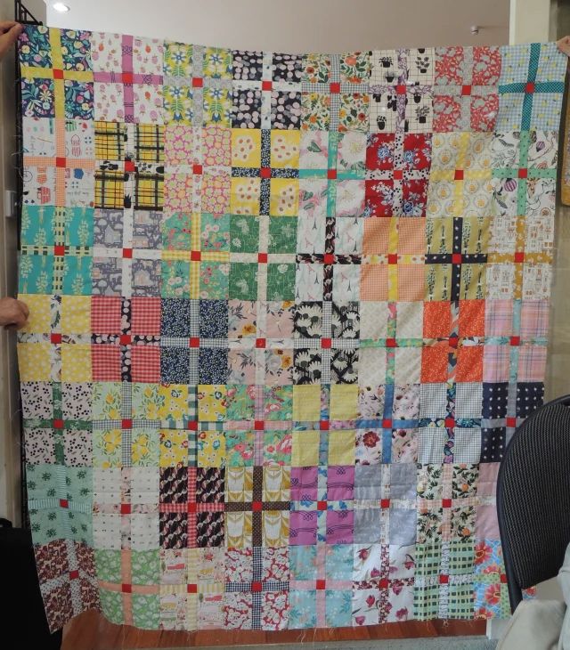 a person is holding up a quilt made with squares