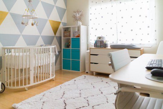 a baby's room with a crib, dresser and desk in the corner