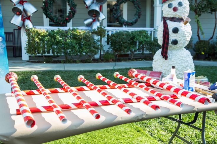 a snowman made out of candy canes sitting in front of a yard decoration