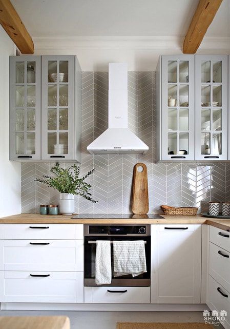 a kitchen with white cabinets and gray tile backsplash