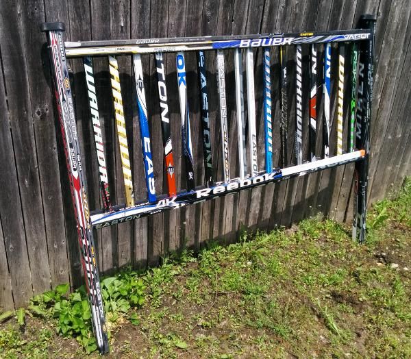 a rack with many different types of skis on it in front of a fence