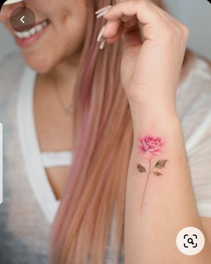 a woman with pink hair and a rose tattoo on her arm