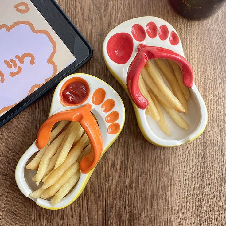 two small plates with french fries and ketchup on them next to a tablet