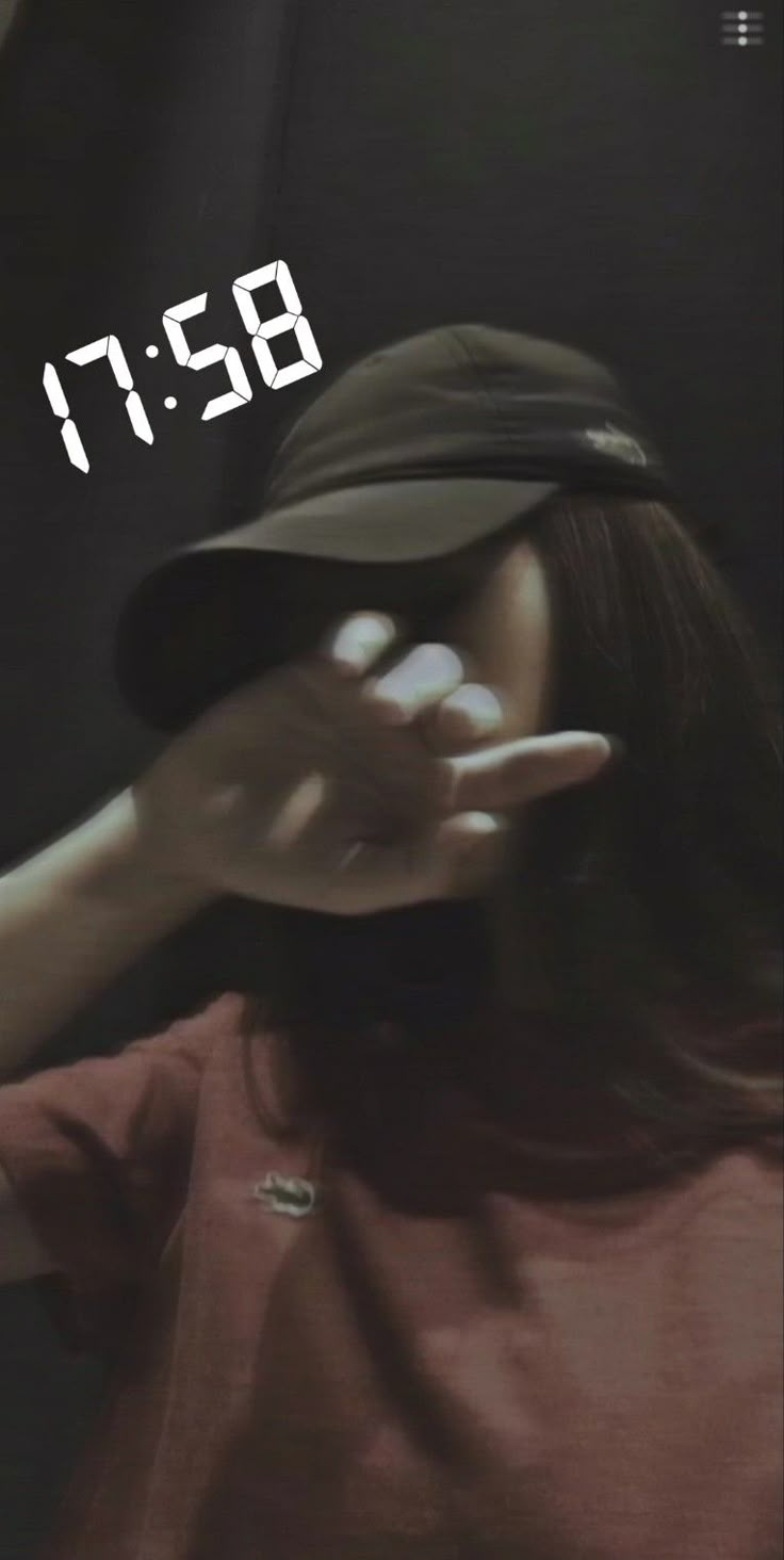 a woman wearing a hat and holding her hand out to the side with an alarm clock on it