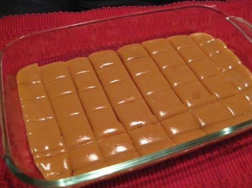 a glass dish filled with chocolate squares on top of a red table cloth and silver serving utensils