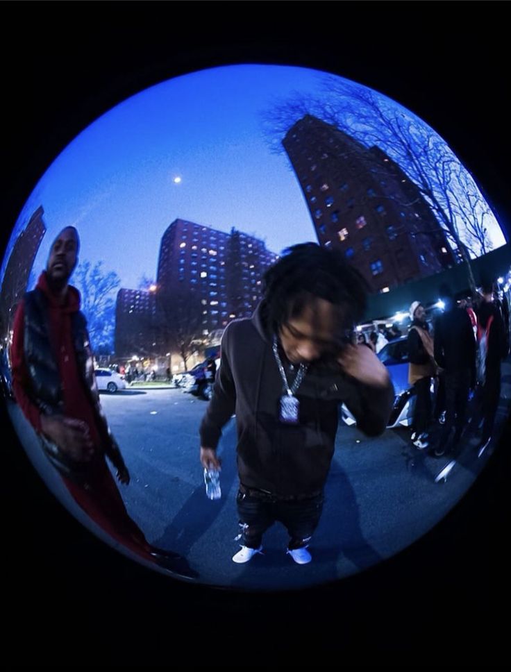 a man standing in the middle of a street next to tall buildings with people walking around