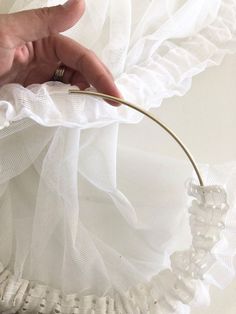 a person holding onto a white piece of cloth with a wire attached to the top