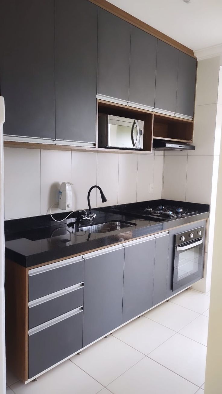 an empty kitchen with black counter tops and gray cupboards on either side of the sink