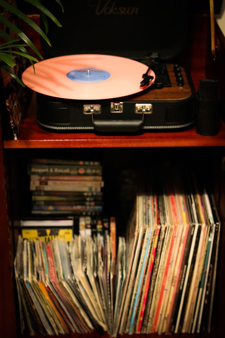 an old record player is sitting on top of a shelf full of records and cds