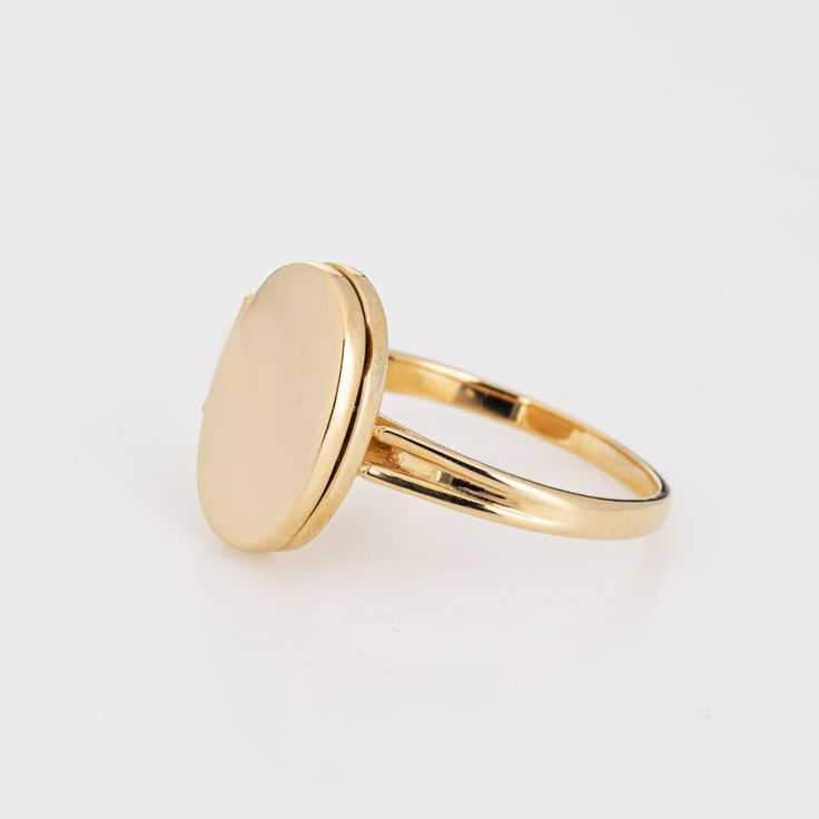 This is part of Chairish’s Fine Jewelry assortment.  Stylish picture locket ring crafted in 14 karat yellow gold.   The oval shaped ring is a wonderful sentimental piece. The locket opens to reveal two sections that can accommodate a picture or keepsake. The low rise ring (5mm - 0.19 inches) sits comfortably on the finger.  The ring is in very good condition and was recently professionally cleaned and polished.   Particulars:  Weight: 3.1 grams  Stones:  N/A   Size & Measurements: The ring is a Timeless Oval Cabochon Signet Ring As Gift, Gold Oval Engraved Ring With Polished Finish, Gold Oval Ring With Polished Finish, Oval Engraved Ring With Polished Finish In Gold, Timeless Gold Oval Engraved Ring, Fine Jewelry Oval Gold Signet Ring, Gold Oval Cabochon Signet Ring For Gift, Gold Oval Cabochon Signet Ring As Gift, Classic Rings With Spring Ring Clasp For Gifts