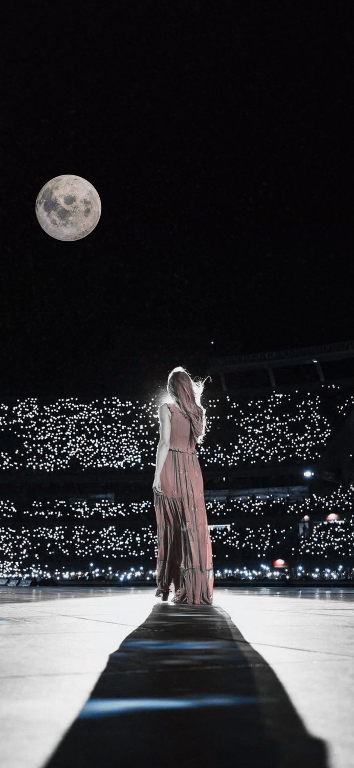 a woman in a long dress is standing on a stage with the moon behind her