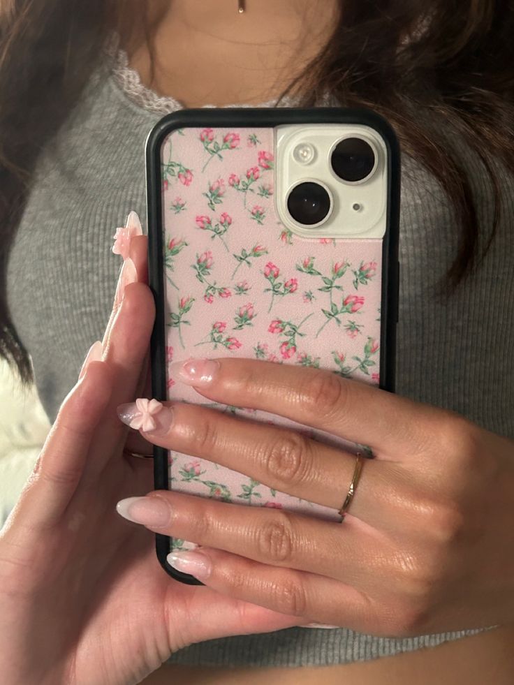 a woman holding up her phone case with flowers on the front and sides, while she's showing off her manicured nails