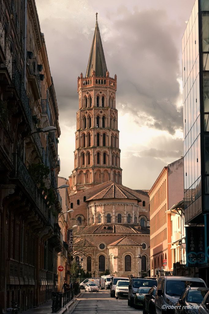 a very tall tower with a clock on it's side in the middle of a city