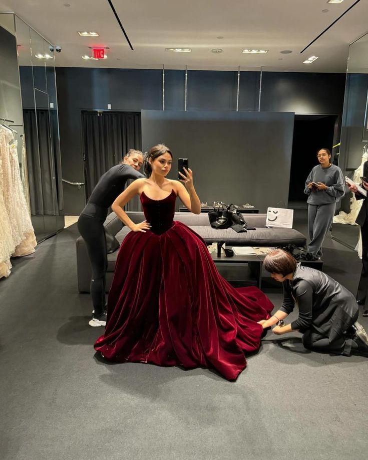 a woman in a long red dress is taking a photo while two men look on