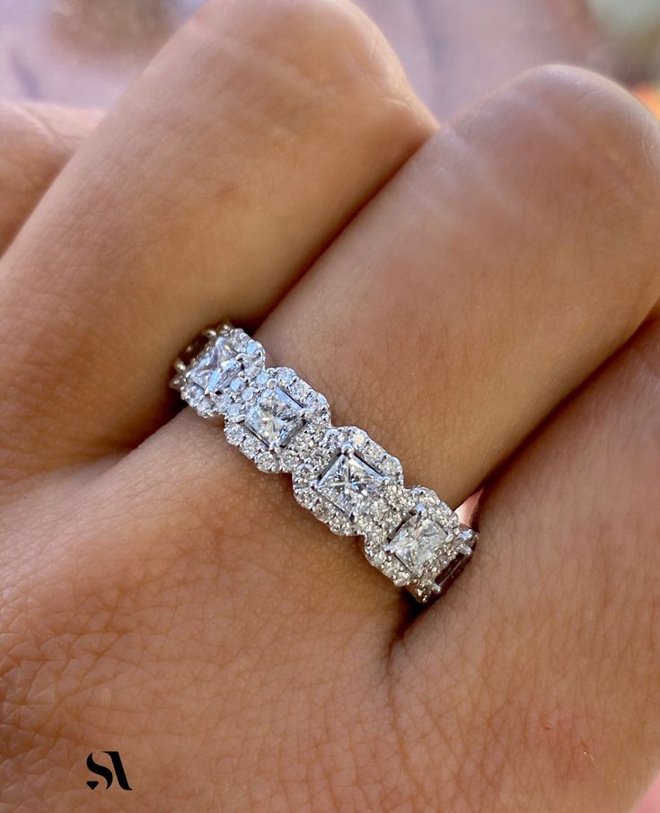 a woman's hand holding an engagement ring with three stones on the middle and sides