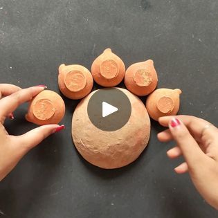 two hands are holding clay balls and pointing at them with their fingers on the top