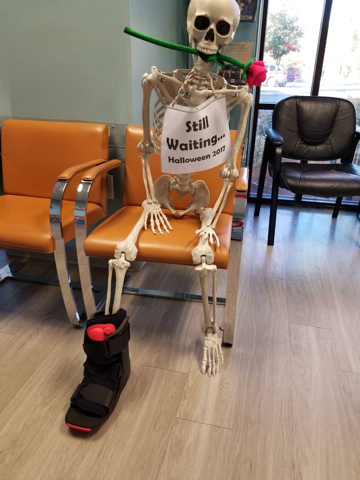 a skeleton sitting on top of a chair with a sign in it's mouth