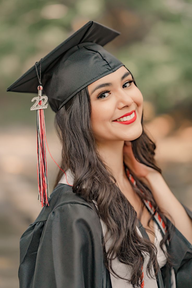 a woman wearing a graduation cap and gown with a tassel around her neck smiles at the camera