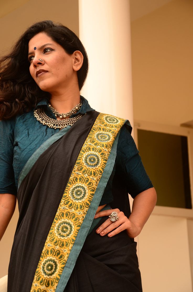 Maya - Carbon black handspun cotton with classic ajrakh printed borders and pallu.  A teal trimming accentuates this piece of another state of elegance. Blouse - Handpicked soft spun cotton - 1 metre. Saree measures standard 5.5 metres in length and 44 inches in height. Patchwork Saree Handmade, Black Cotton Dupatta With Traditional Patterns, Bohemian Cotton Dupatta With Border, Black Block Print Dupatta With Traditional Drape, Black Chanderi Dupatta With Printed Border, Black Cotton Saree With Traditional Drape, Black Saree With Block Print And Traditional Drape, Black Cotton Saree For Festivals, Black Bohemian Embroidered Saree