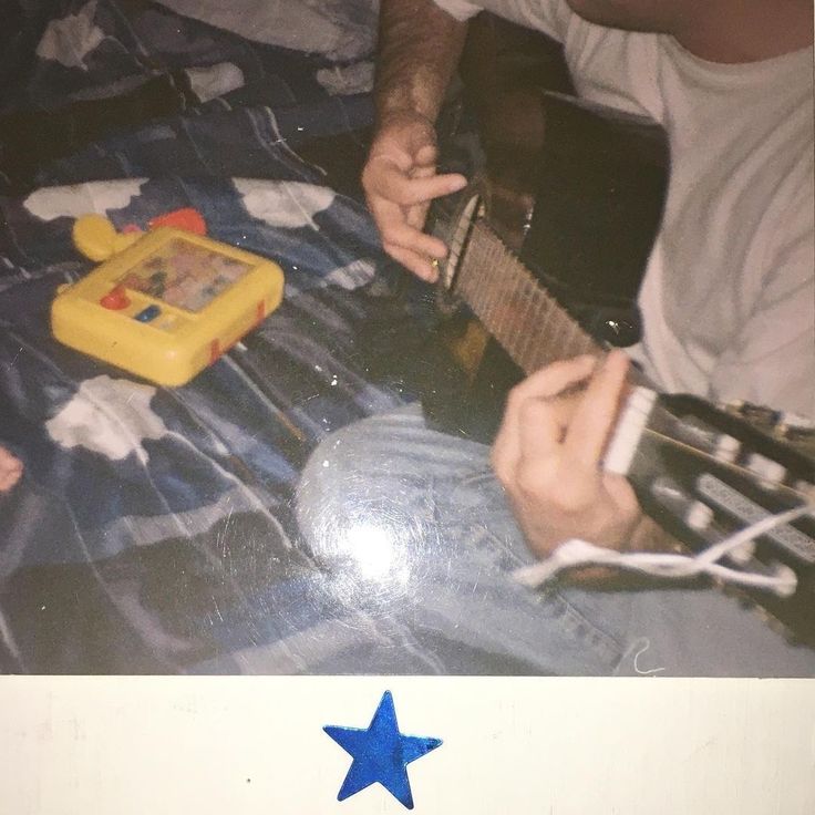 a man playing an electric guitar with a blue star on the bottom of his shirt