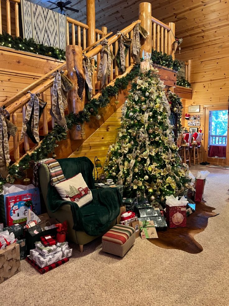 a christmas tree in the middle of a living room with presents on the floor and stairs