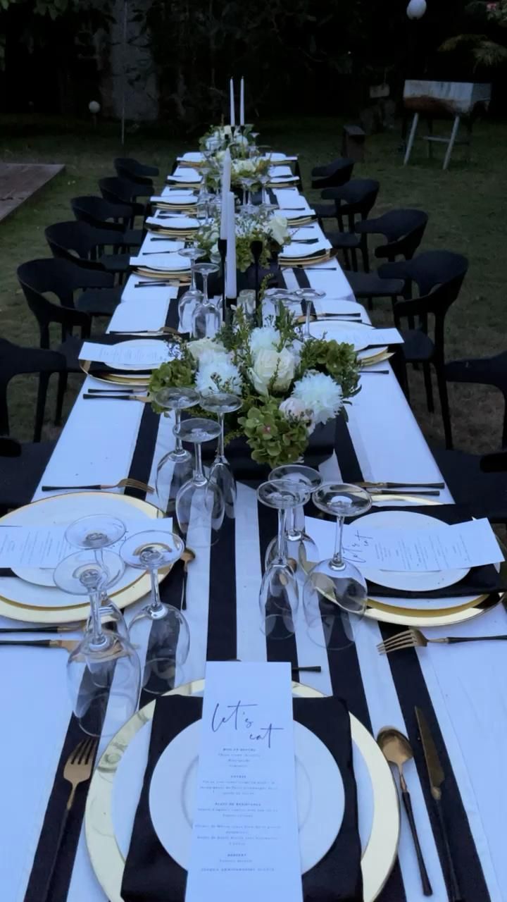 the table is set with black and white striped linens, silverware, and flowers