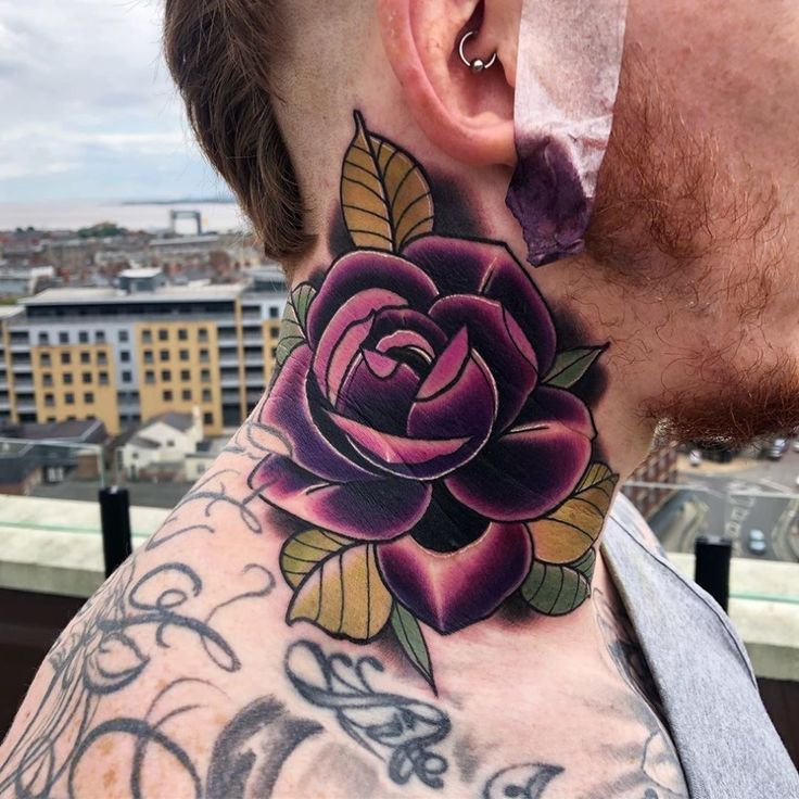 a man with a rose tattoo on his neck is looking at the city from behind him