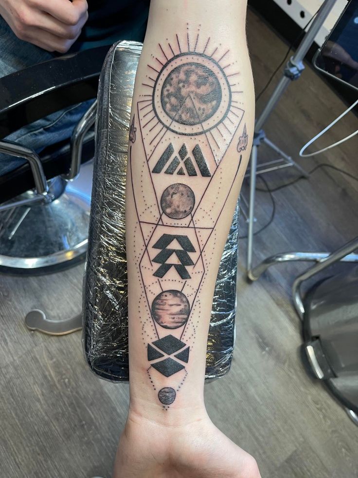 a person with a tattoo on their arm that has the sun and planets in it