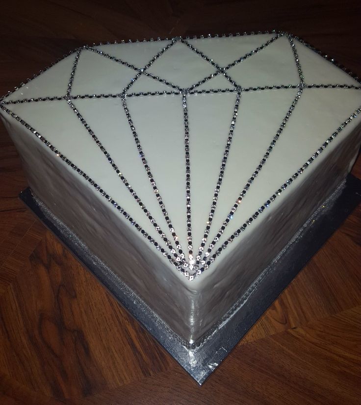 a cake with white frosting and black beading on the top is sitting on a wooden table