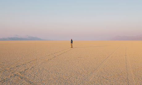 a lone person standing in the middle of an empty desert