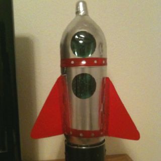 a silver and red rocket ship sitting on top of a wooden table