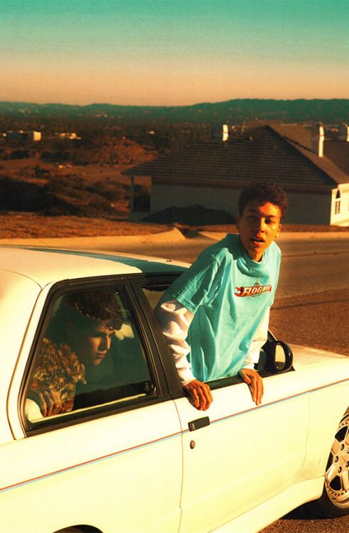 a young man leaning out the window of a white car