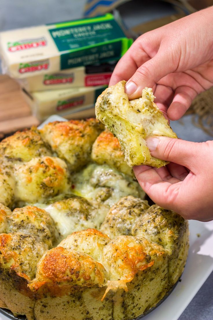 a person is dipping something into a bread dish with cheese and broccoli on top