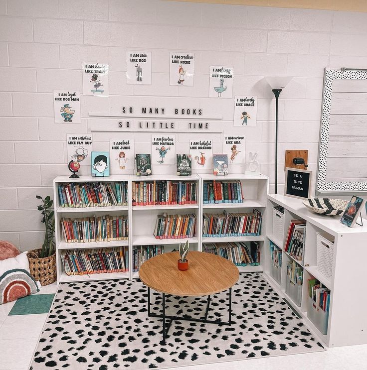 a room with several bookshelves and a coffee table in the center, along with posters on the wall