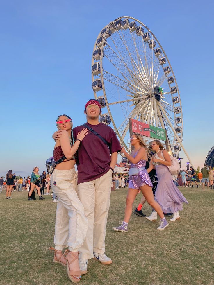 two people standing next to each other in front of a ferris wheel