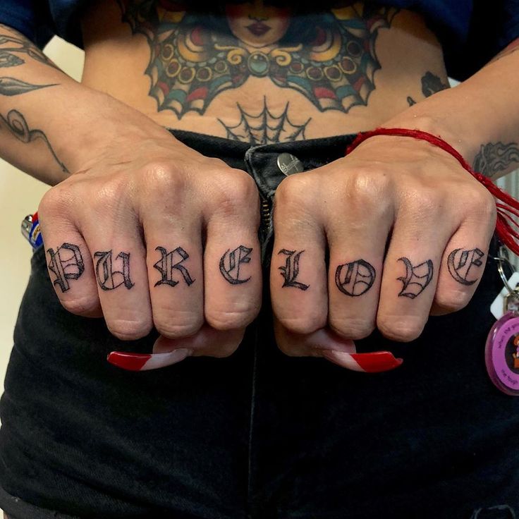 a person with tattoos on their hands holding two fingers