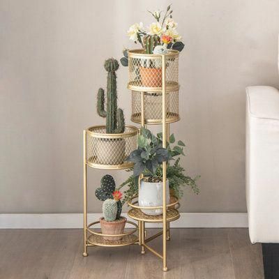 three tiered plant stand with potted plants on each shelf and two white couches in the background