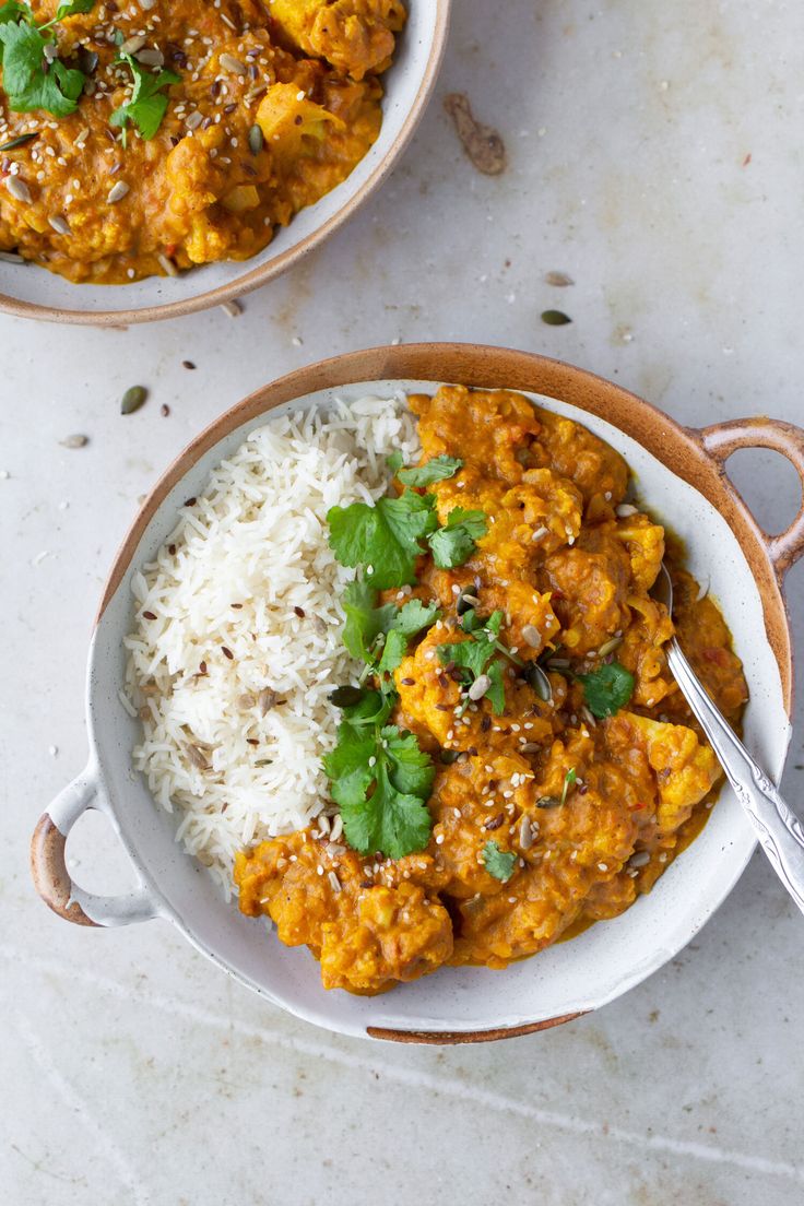 two bowls filled with curry and rice on top of a table