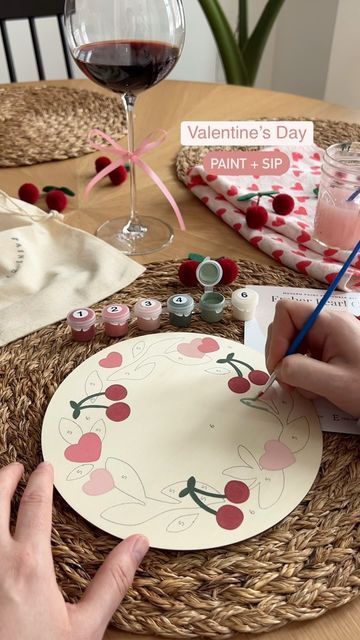 someone is painting a plate with cherries on it