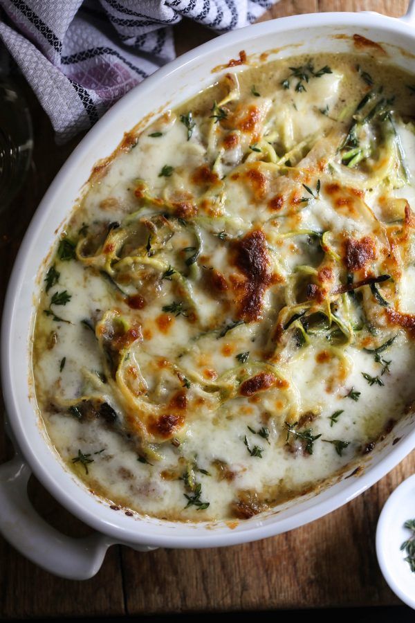 a casserole dish with spinach, cheese and sauce in it on a wooden table