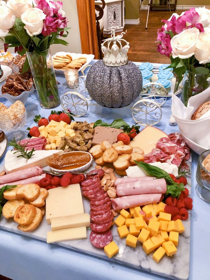 a table topped with lots of different types of cheese and meats next to flowers