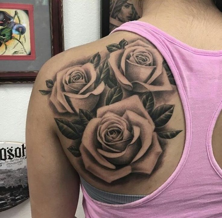 a woman's back with three roses tattooed on her upper and lower half sleeve