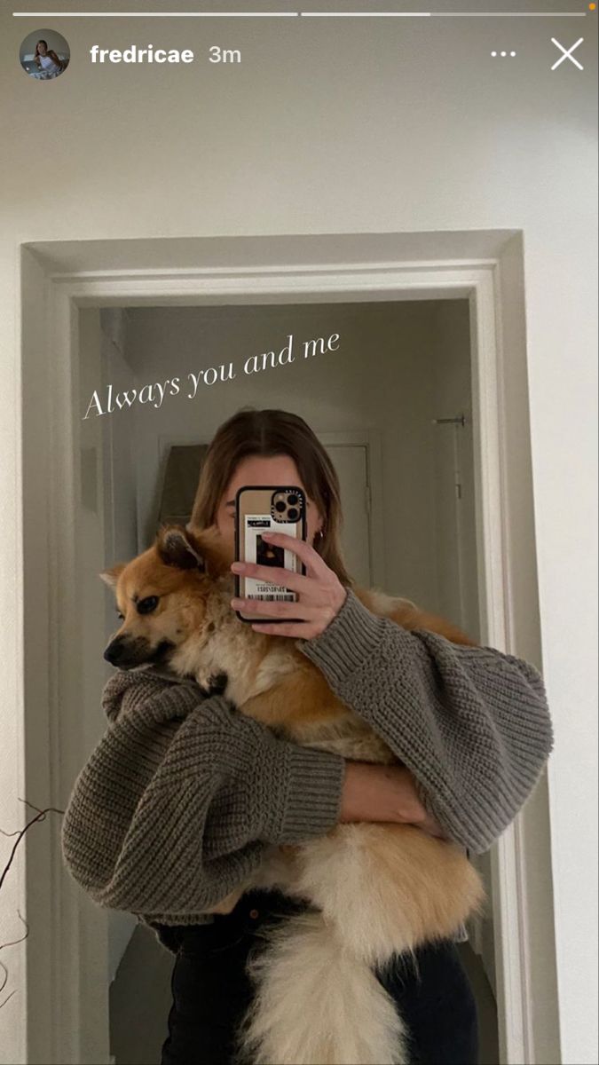 a woman holding a dog and taking a selfie with her camera in the mirror